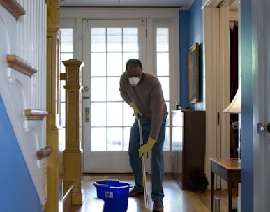 man in gray hoodie and blue denim jeans standing on brown wooden parquet flooring