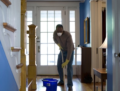 man in gray hoodie and blue denim jeans standing on brown wooden parquet flooring