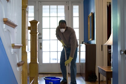 man in gray hoodie and blue denim jeans standing on brown wooden parquet flooring