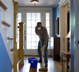 man in gray hoodie and blue denim jeans standing on brown wooden parquet flooring