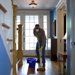 man in gray hoodie and blue denim jeans standing on brown wooden parquet flooring