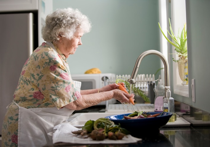 woman in purple and white floral shirt sitting on white bed