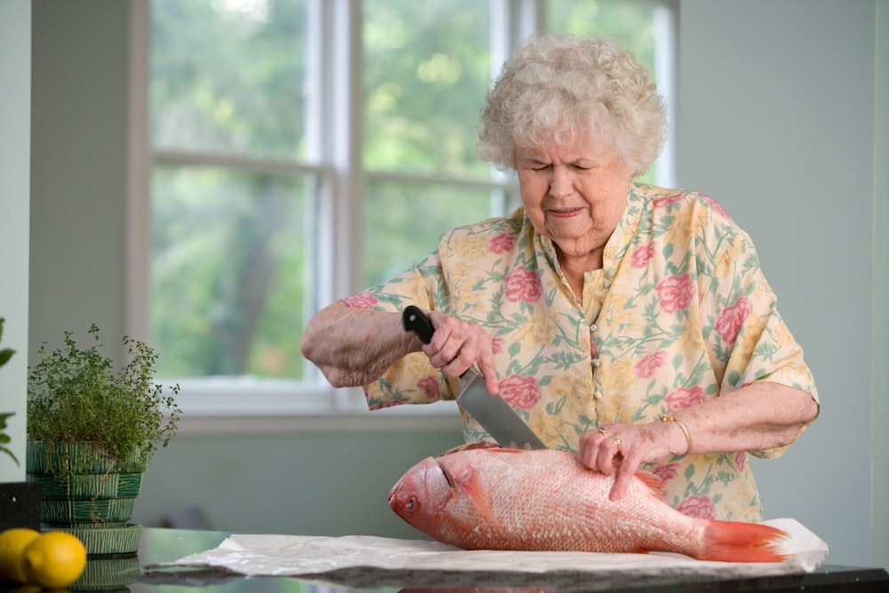 donna in merda floreale gialla e rosa che tiene un pesce fresco 