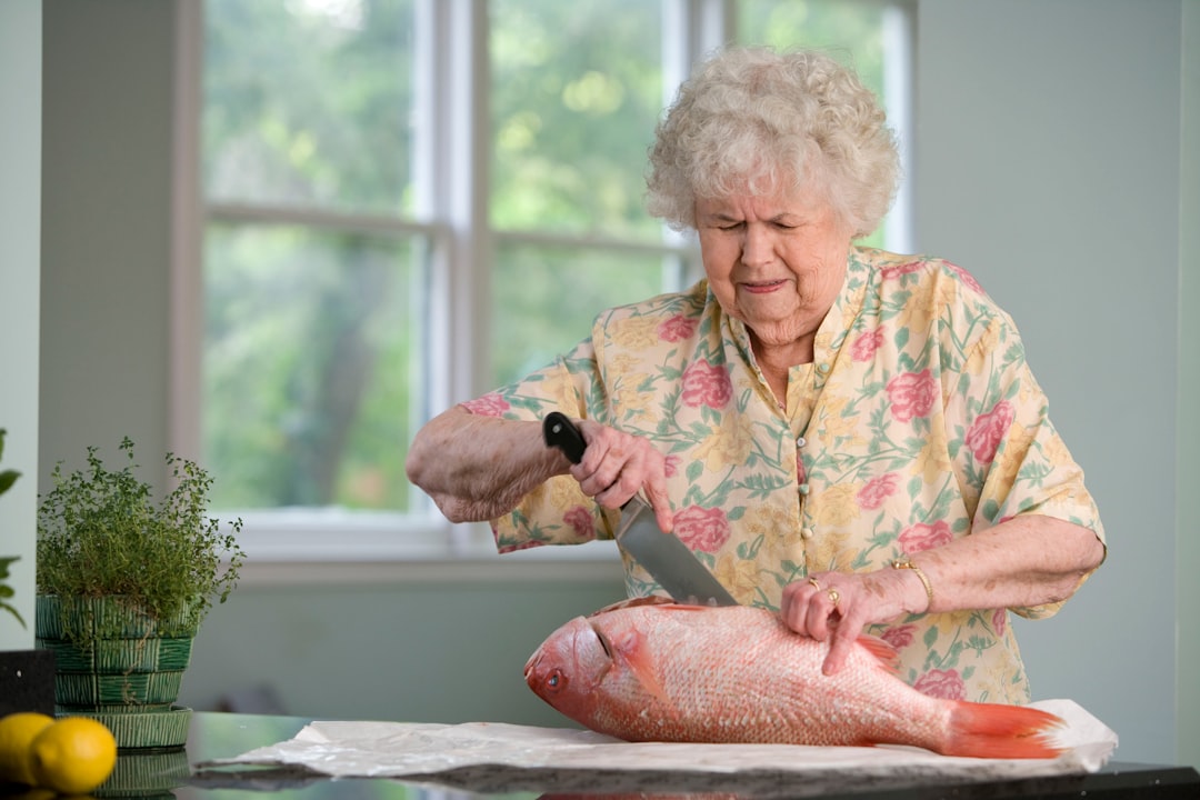 This elderly woman was in the process of preparing a fresh fish on her clean kitchen counter. Carefully using a large knife, the woman had cut into the fish’s belly, and would subsequently extract the internal organs prior to finally cutting away the fillets.