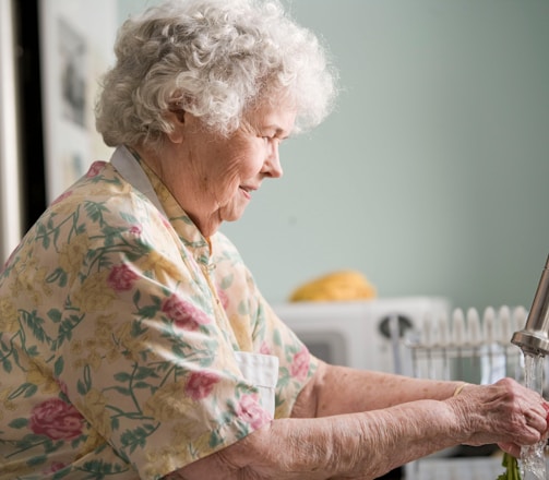 woman in yellow and green floral shirt holding white ceramic mug