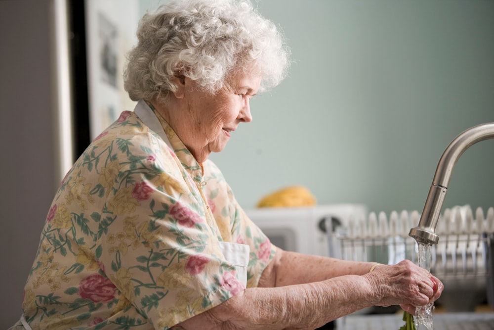 woman in yellow and green floral shirt holding white ceramic mug