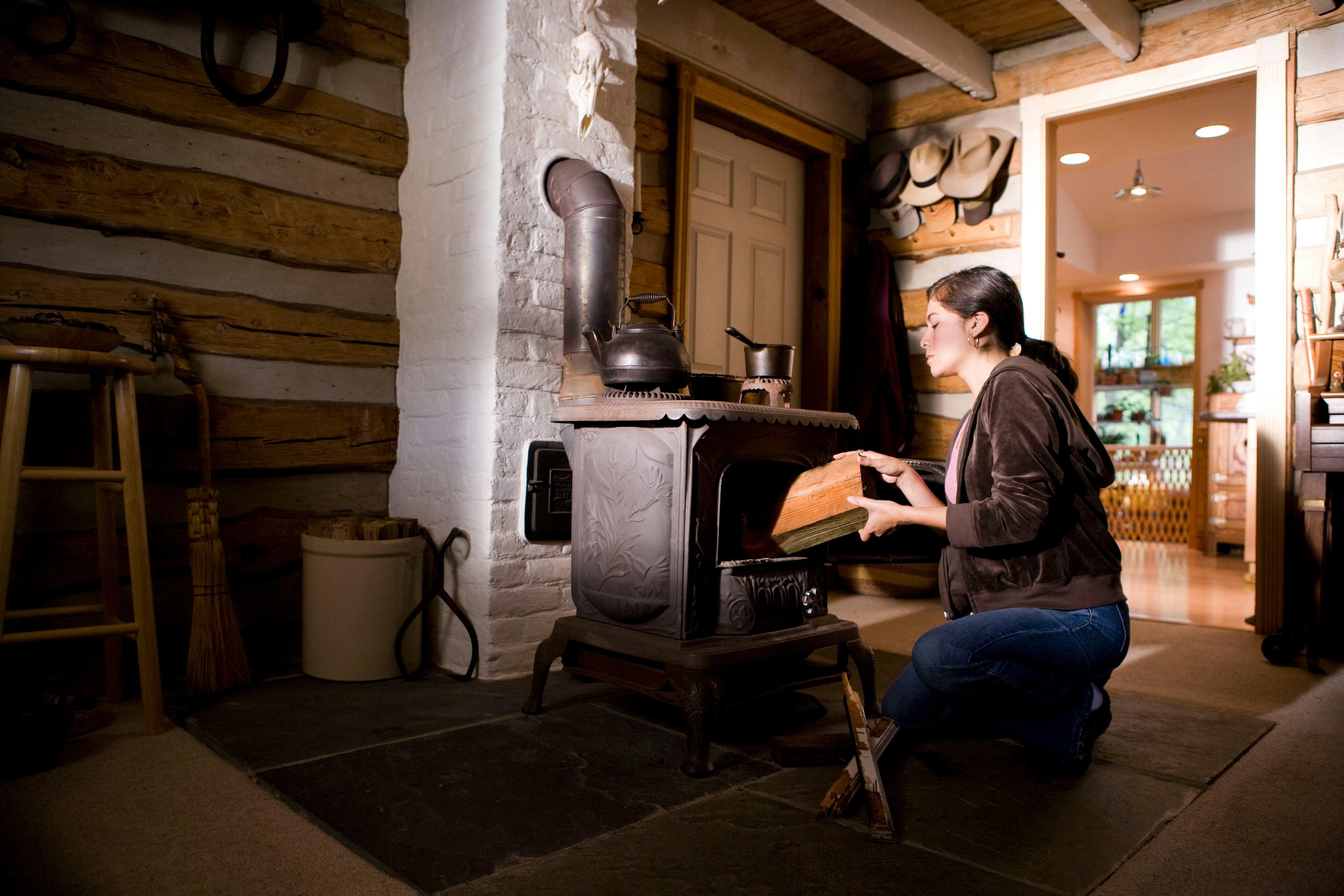 This home’s interior, though beautiful, houses a potential hazard on many levels, therefore, special care need be taken in order to safely operate this wood-burning stove, for not only does it generate a terrific amount of heat, it does so using flame, rather than electricity, which is much more difficult to control. This woman was about to place what appears to be a piece or treated lumber into the stove as fuel.