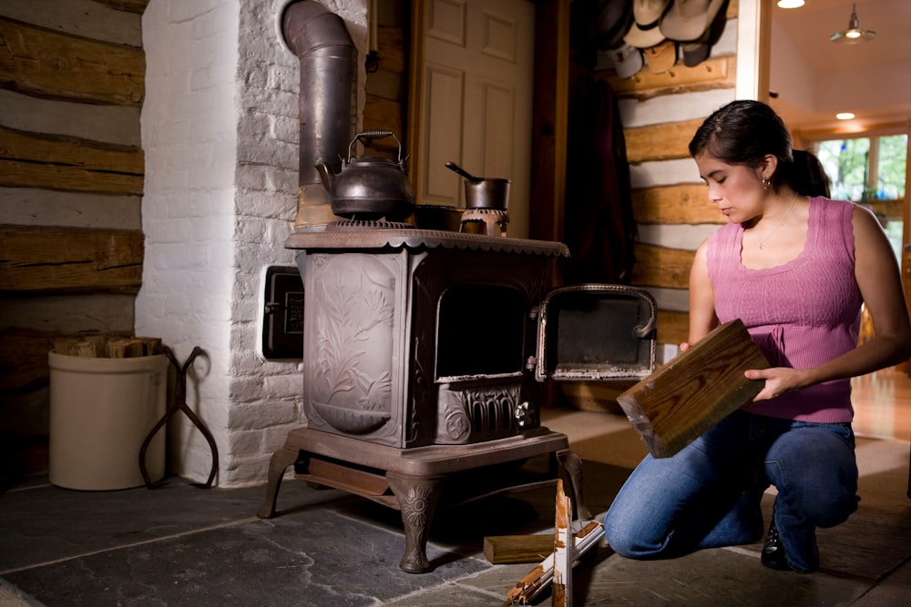 woman in pink shirt and blue denim jeans sitting on brown wooden chair