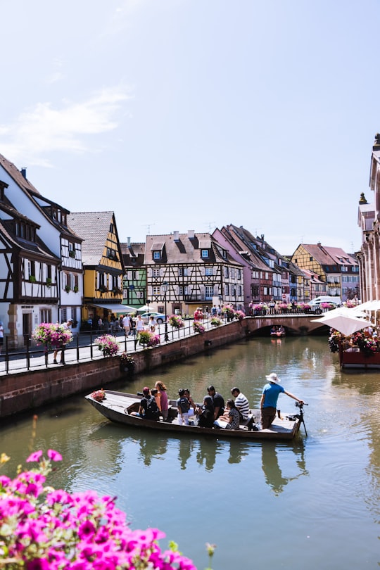 people riding on boat on river between houses during daytime in La Petite Venise France