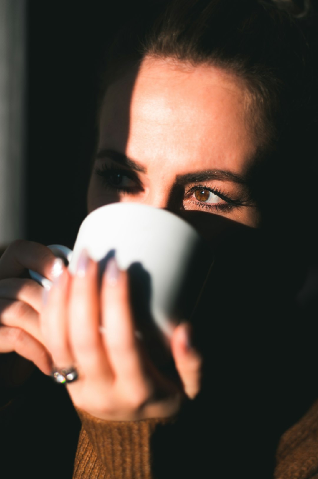 woman covering her face with white ceramic mug
