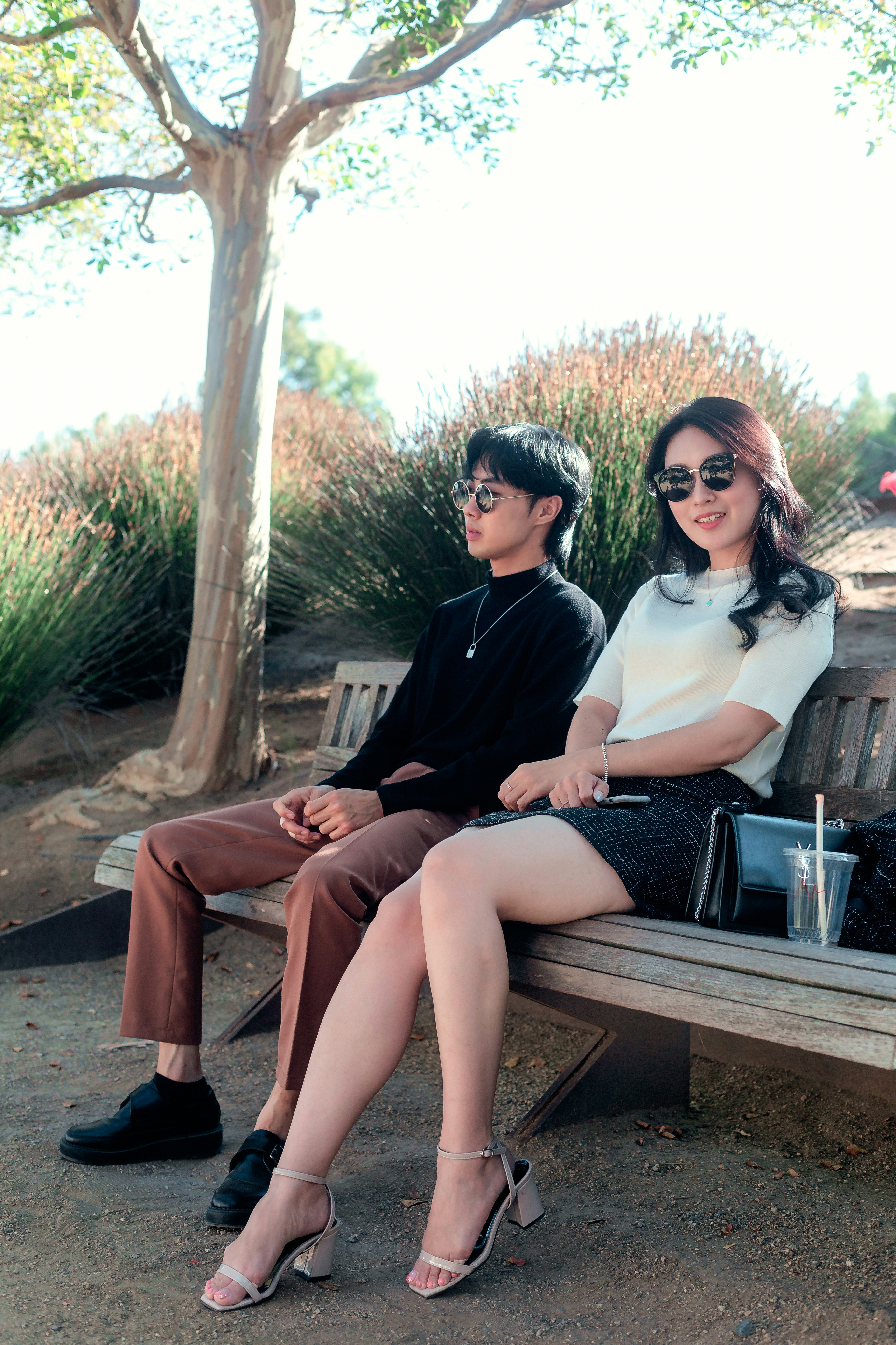 man and woman sitting on brown wooden bench during daytime