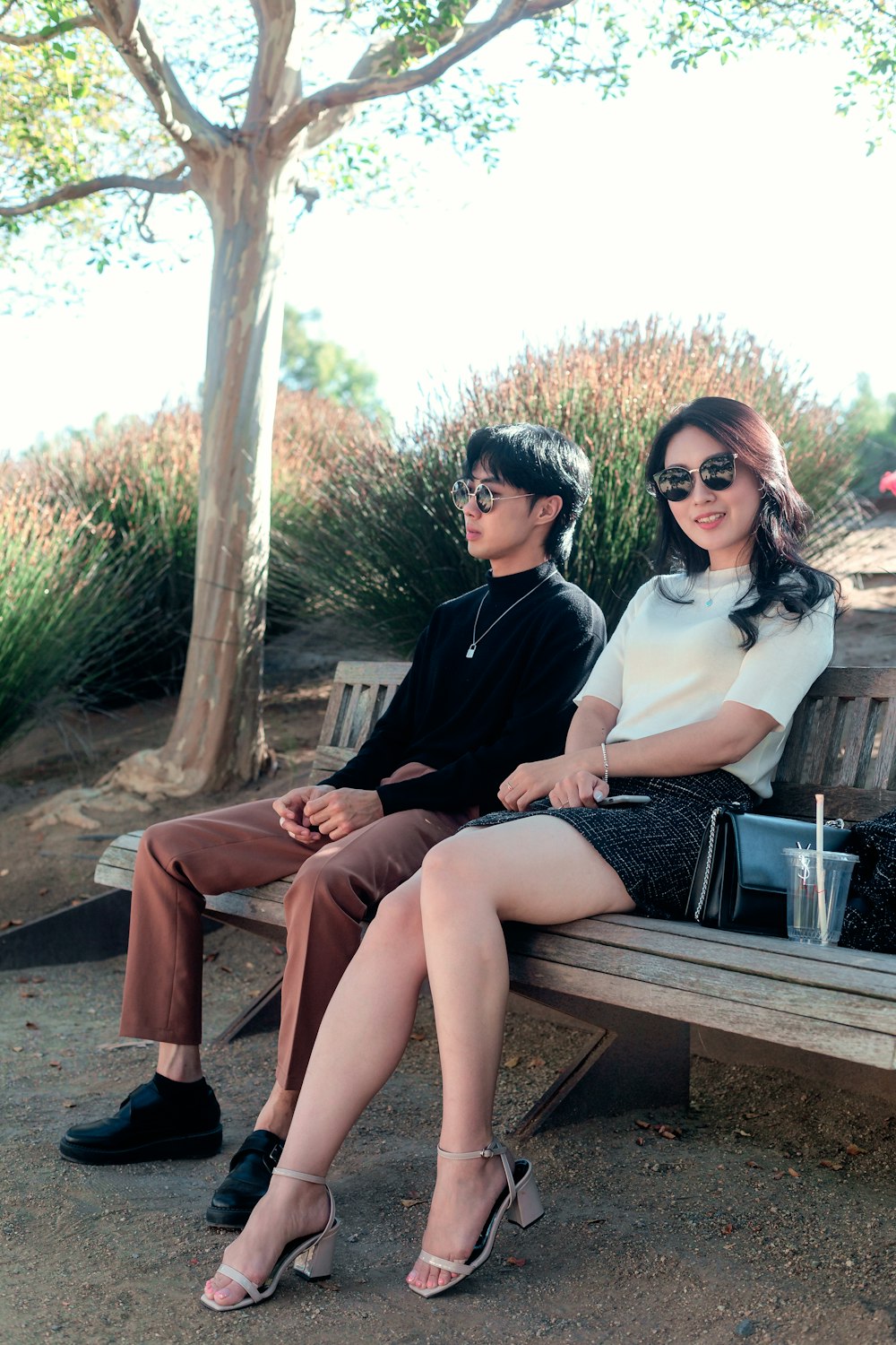 uomo e donna che si siedono sulla panca di legno marrone durante il giorno
