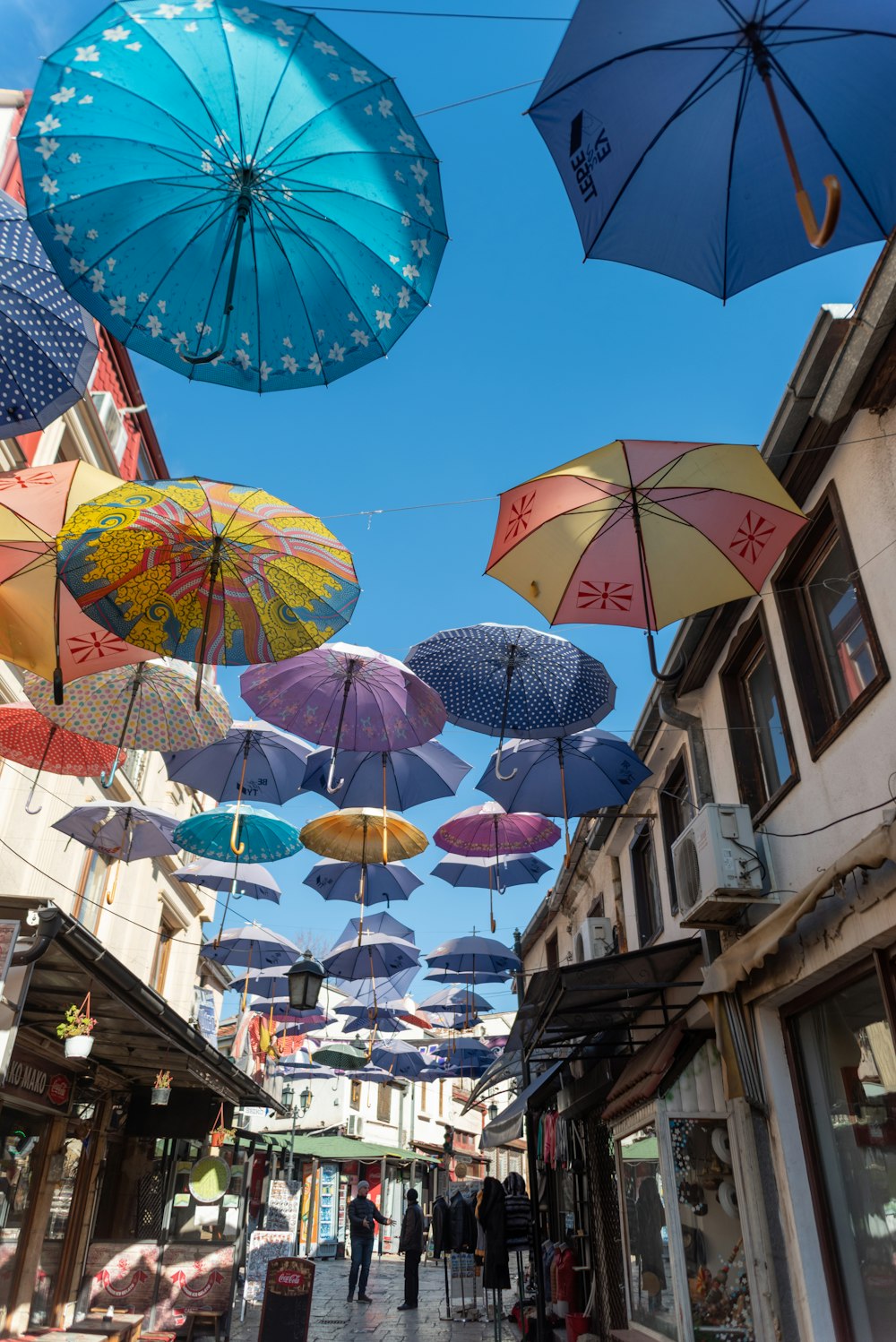 assorted umbrellas hanging on wire during daytime