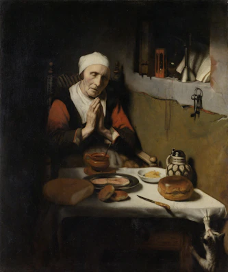 A Christian family holding hands in prayer around the dinner table in soft morning light.