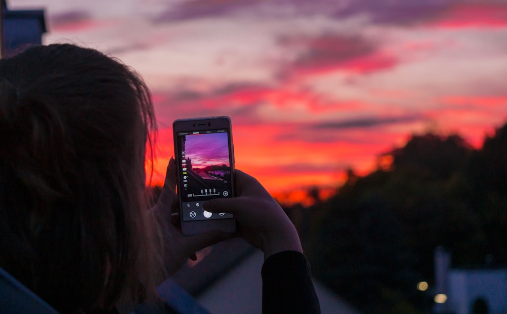 mulher que tira a foto do pôr do sol