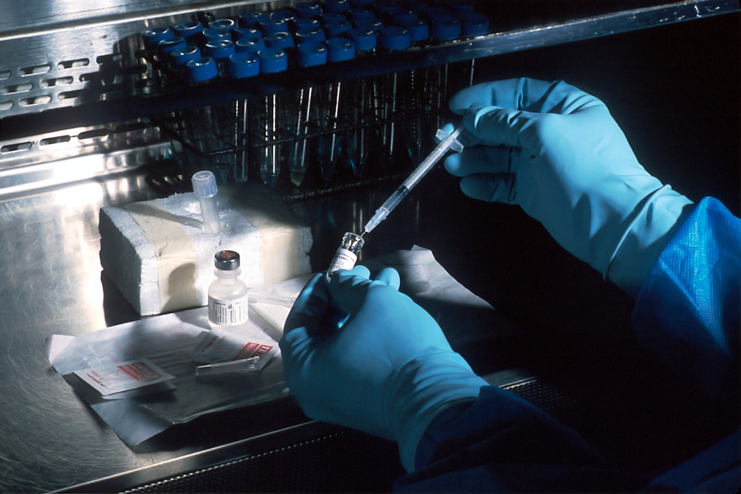 person holding silver and black hand tool, Vaccine. Hands of a scientist, under a sterile hood, preparing the carcinoembryonic antigen (CEA) vaccinia used to try to prevent cancer. The scientist is diluting the concentrated vaccinnia virus into a dose level appropriate for administration to a patient. This vaccinnia marks any cancer cells expressing the CEA.