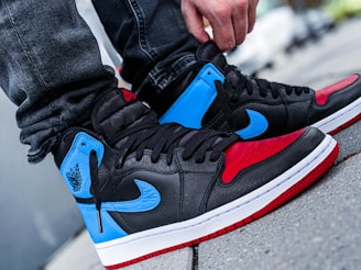 A close-up of a sneakerhead tying the laces on a vibrant pair of streetwear sneakers.