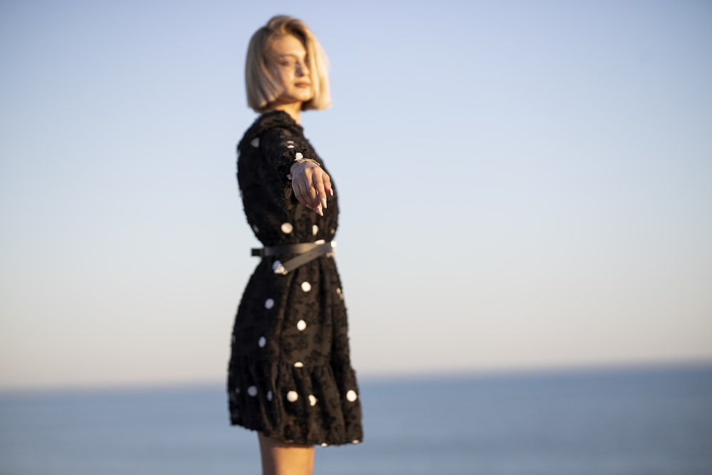 woman in black long sleeve dress standing on seashore during daytime