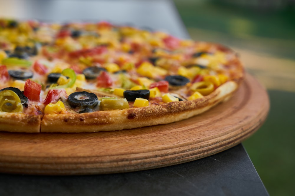 Pizza aux fruits verts et rouges et aux baies noires sur assiette ronde en bois brun