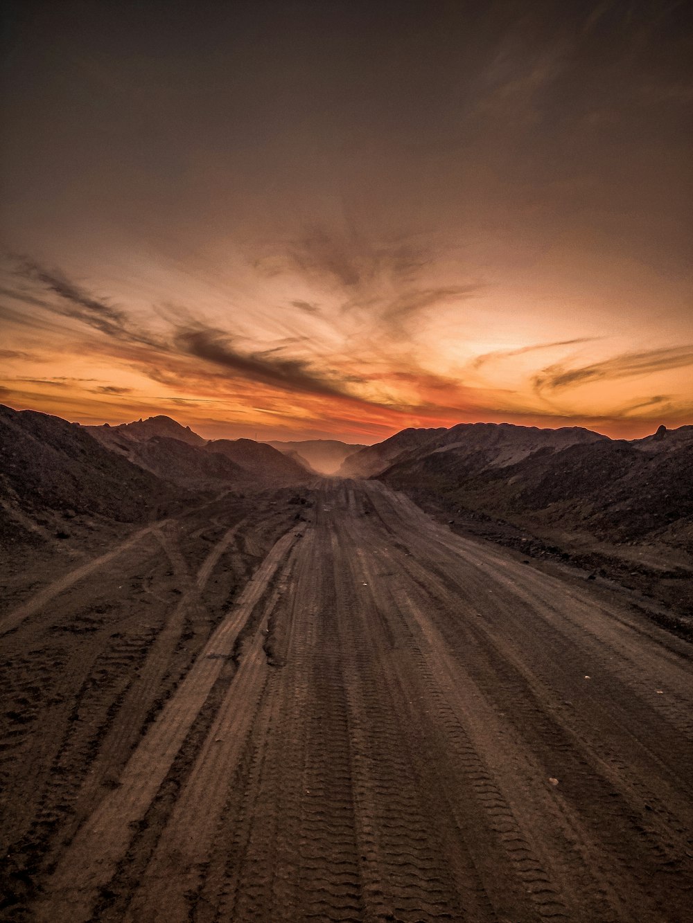 Campo marrón cerca de la montaña bajo el cielo naranja