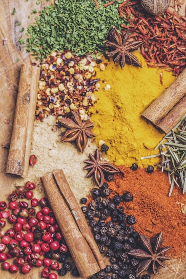 Close-up of vibrant Indonesian spices including nutmeg, peppercorns, and candlenuts arranged on a rustic wooden surface.