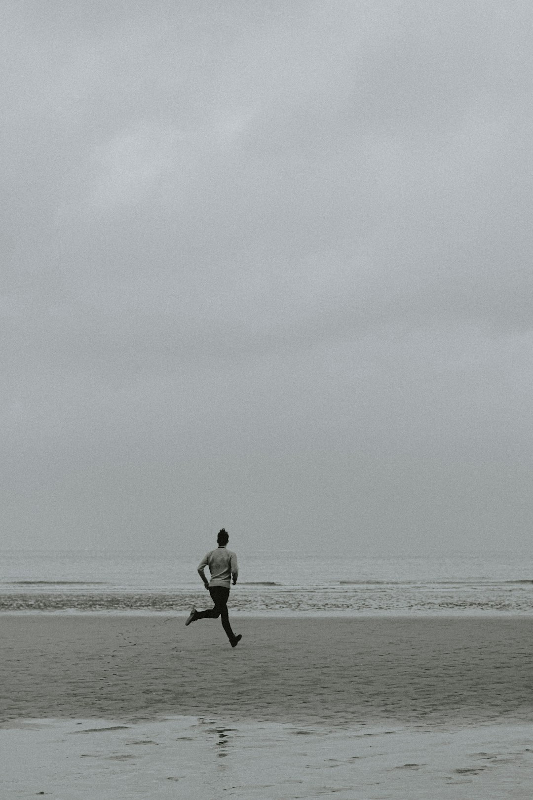 man in white shirt and black pants walking on beach during daytime