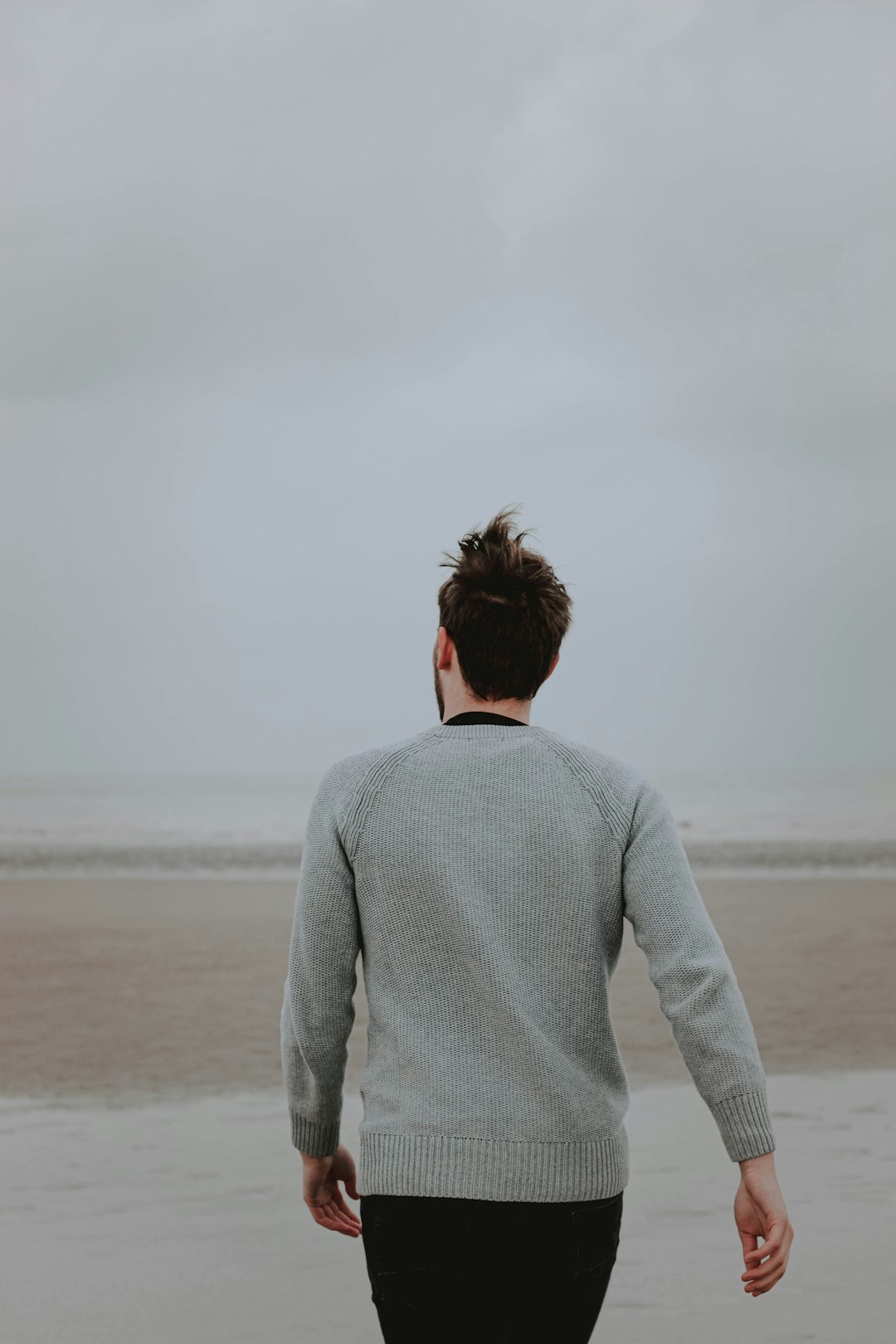 woman in gray long sleeve shirt standing on beach during daytime
