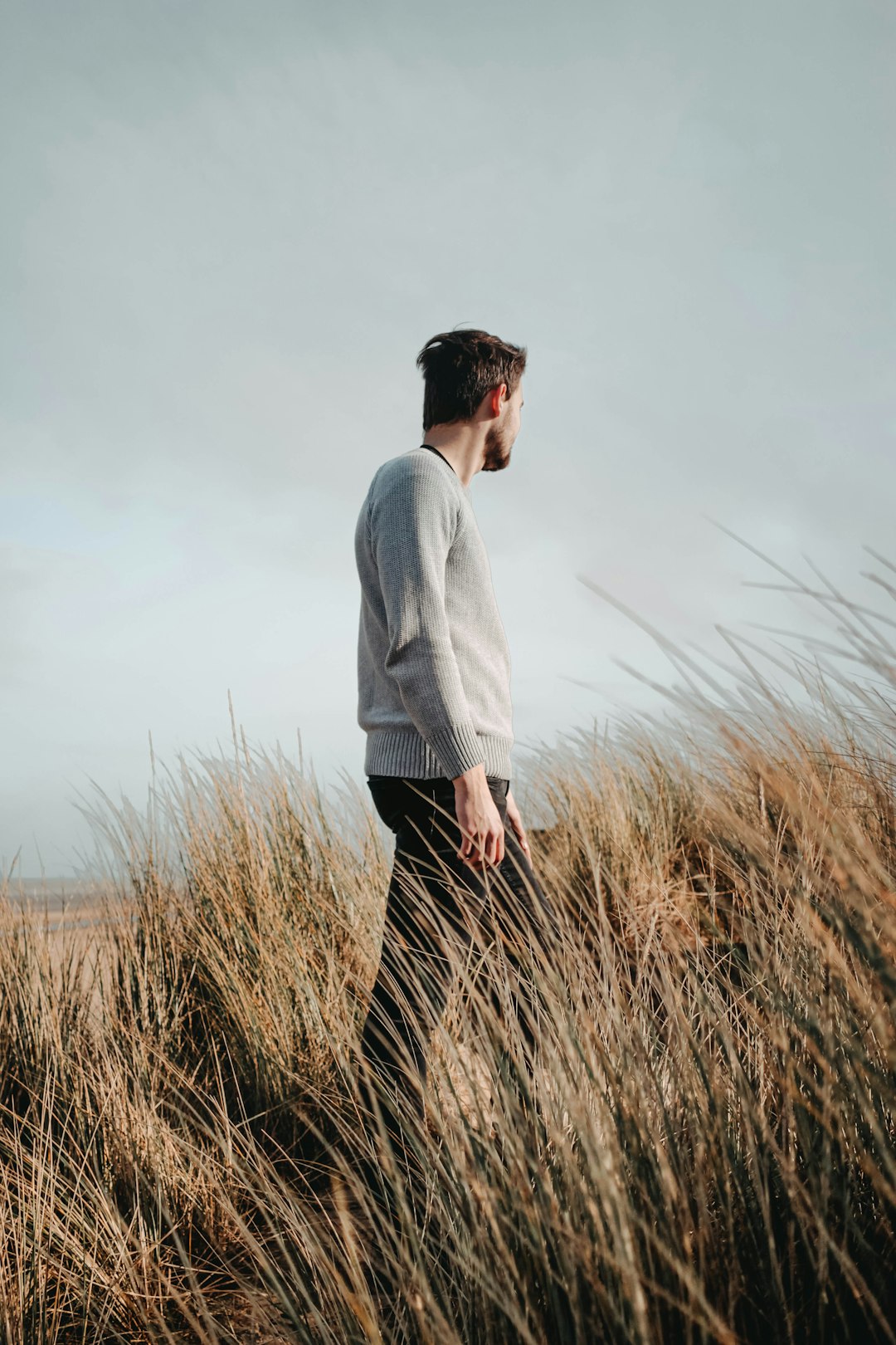 man in gray long sleeve shirt standing on brown grass field during daytime