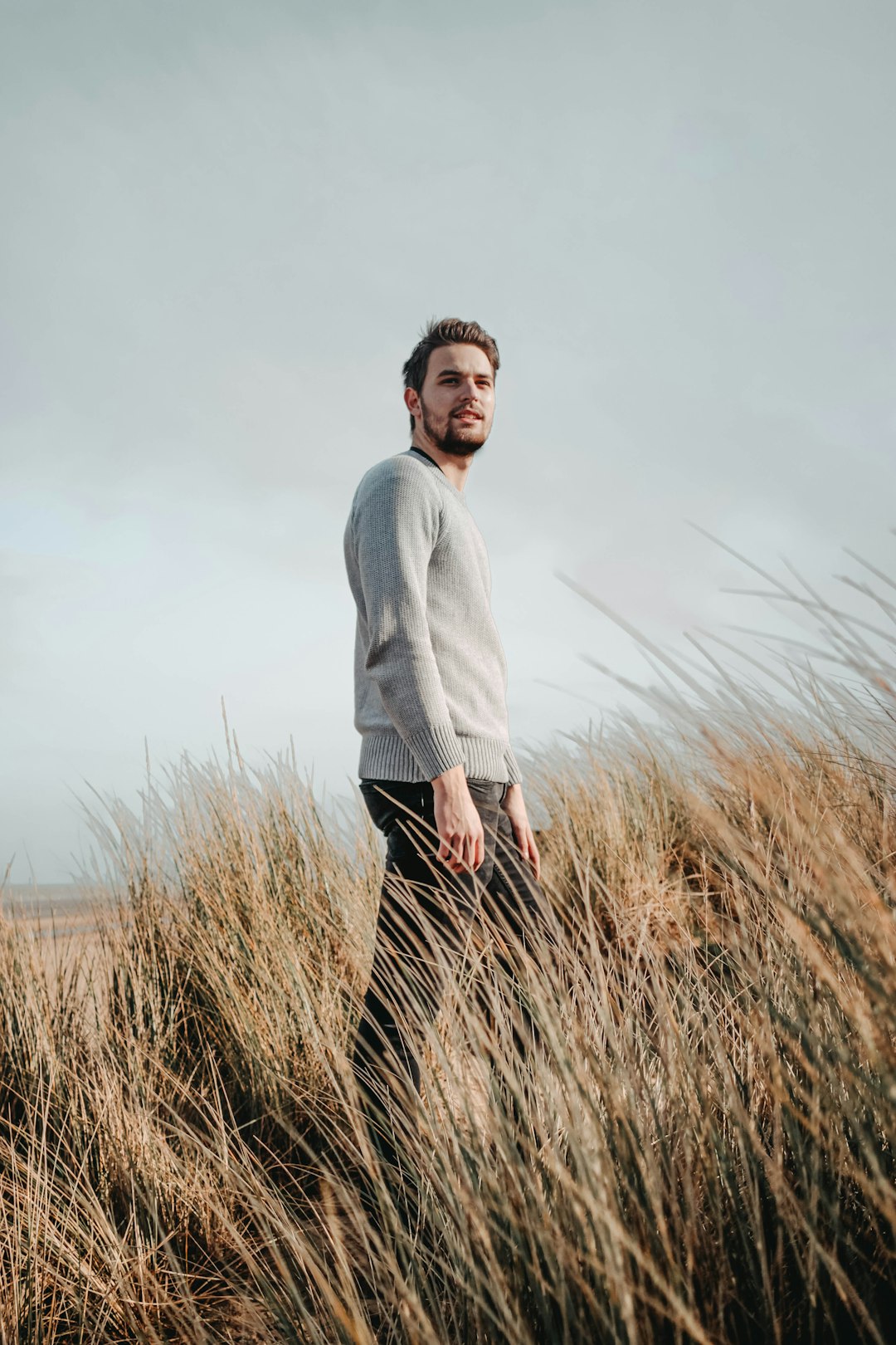 man in white dress shirt standing on brown grass field