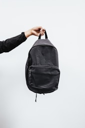 person in black jacket holding black backpack