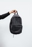 person in black jacket holding black backpack