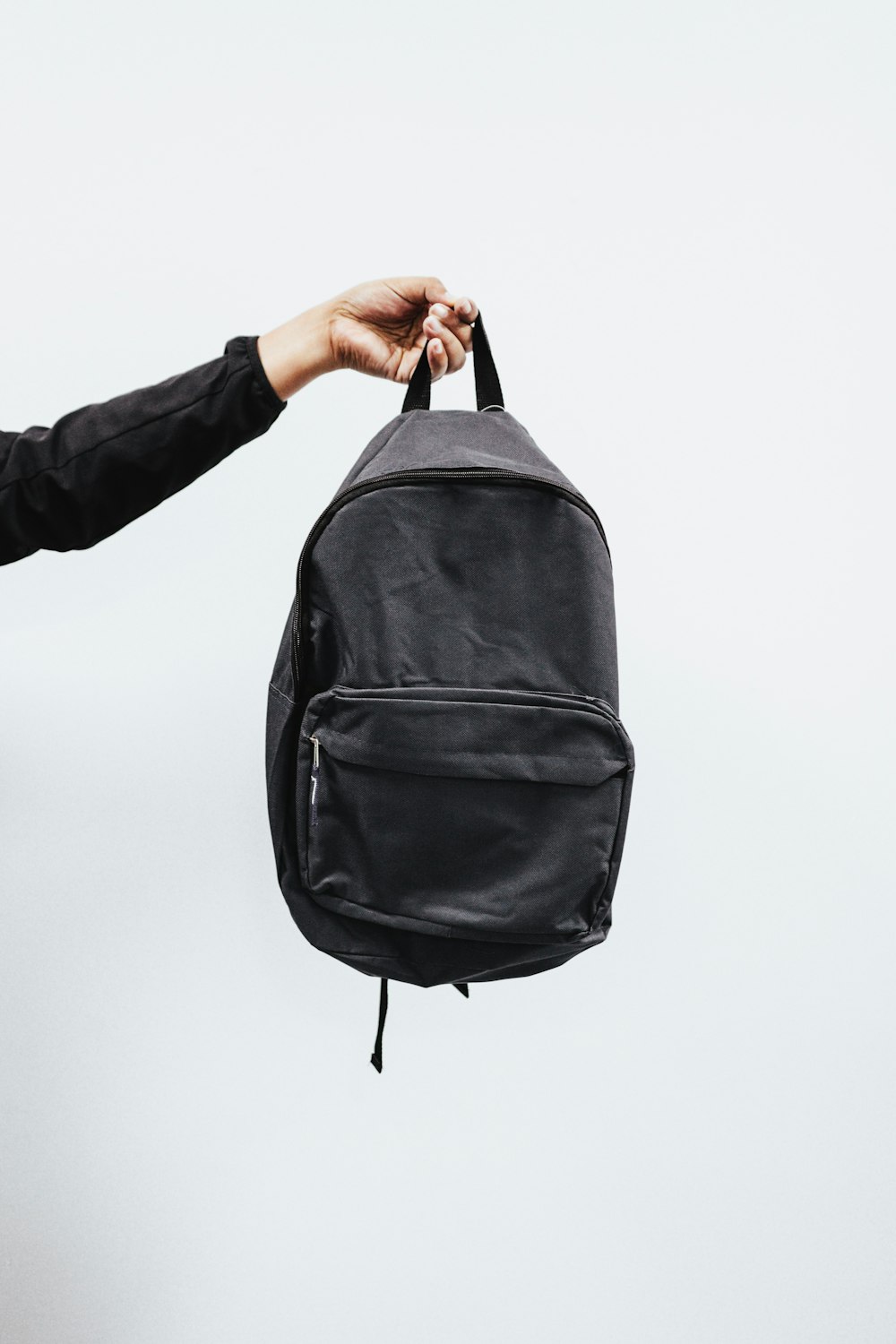 person in black jacket holding black backpack