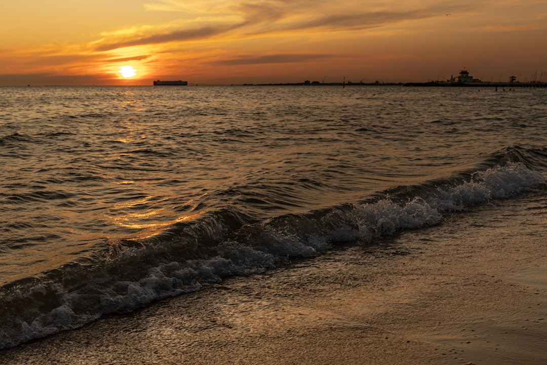 ocean waves crashing on shore during sunset