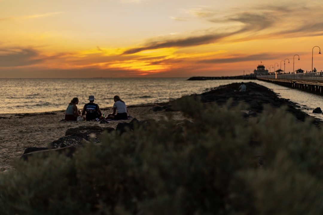 people sitting on rock near sea during sunset