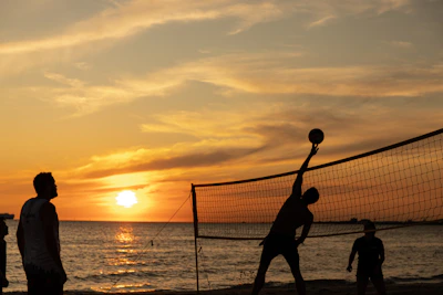 Young volleyball players practicing on an outdoor court during sunset.