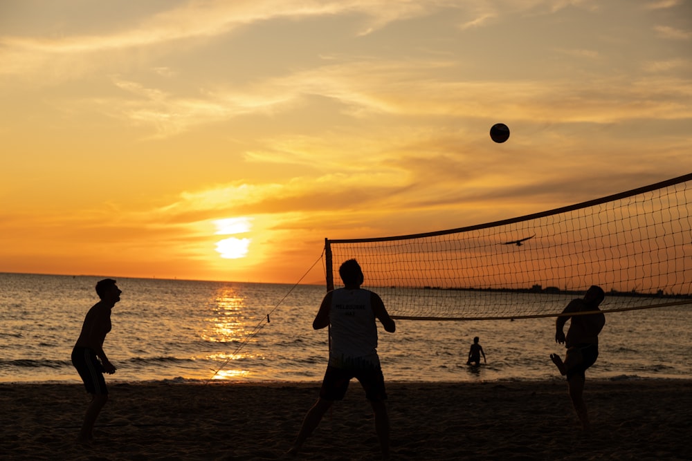 silhouette of people playing beach volleyball during sunset