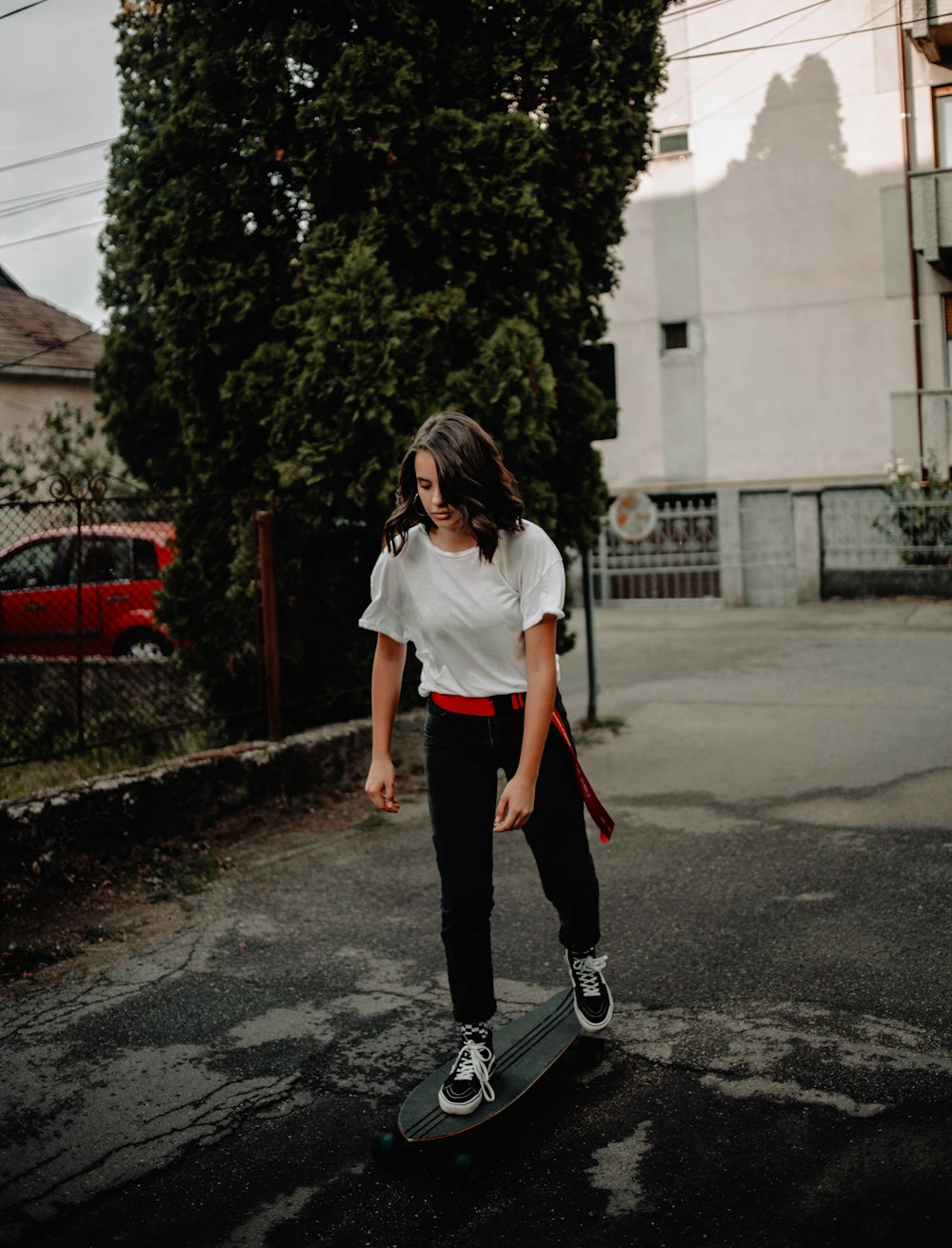 woman in white t-shirt and black pants walking on street during daytime