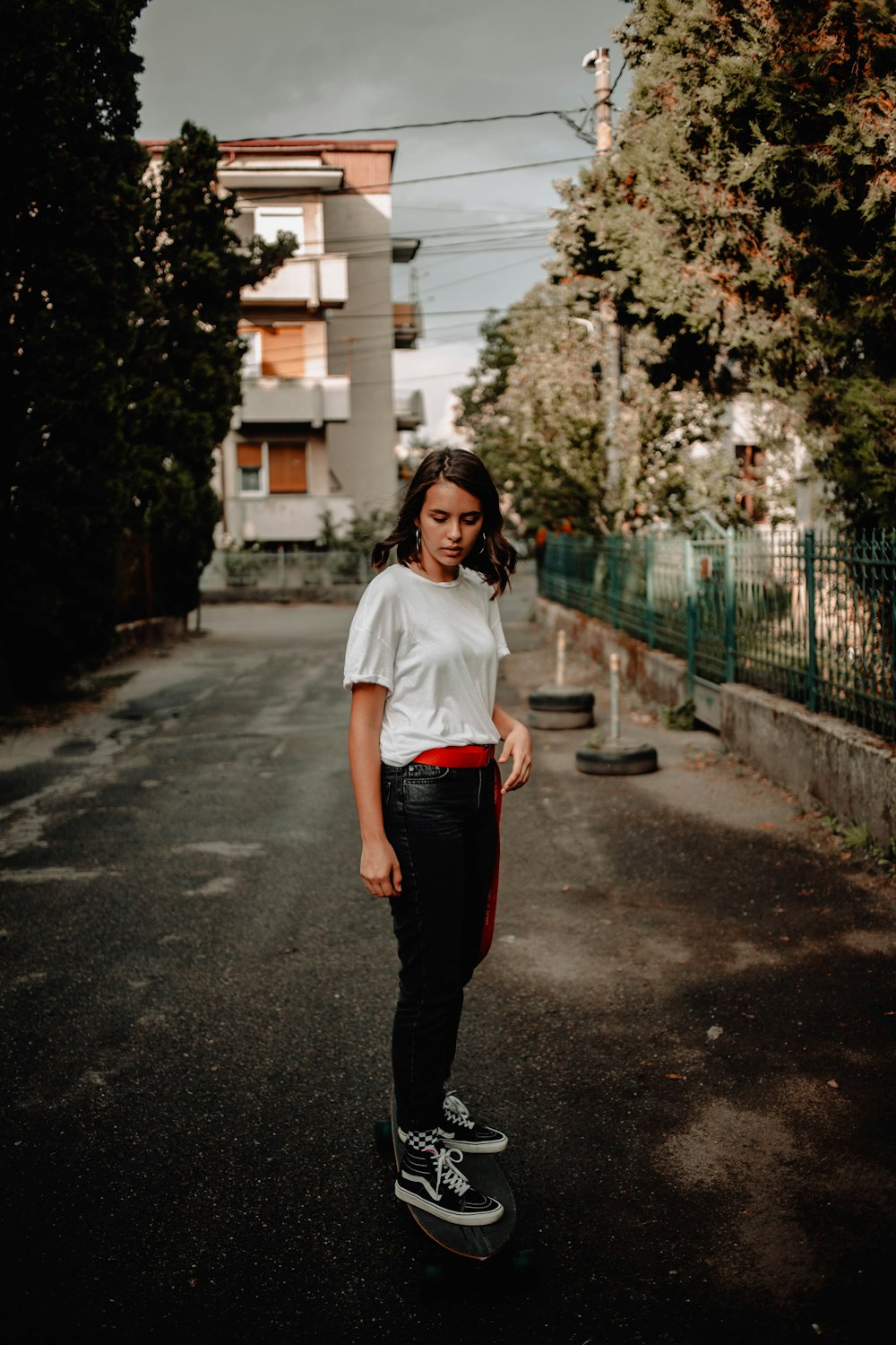 woman in white t-shirt and black pants standing on road during daytime