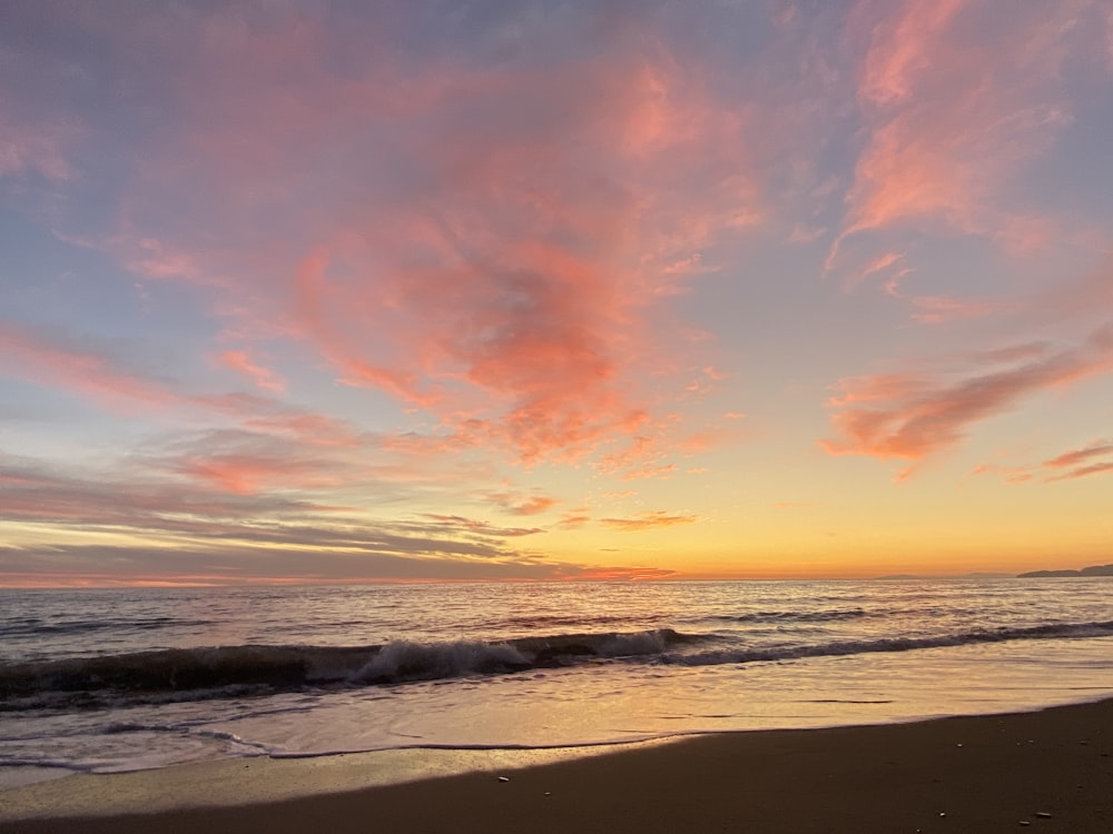 sea waves crashing on shore during sunset