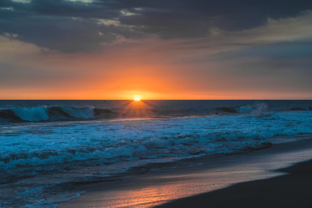 ocean waves crashing on shore during sunset