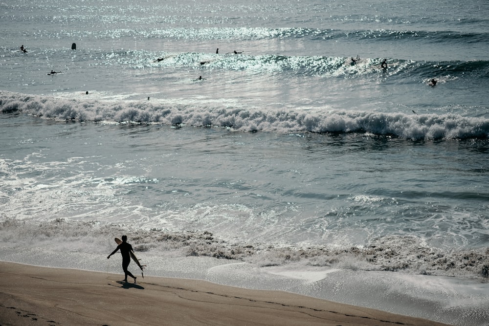 Mann in schwarzen Shorts tagsüber am Strand spazieren