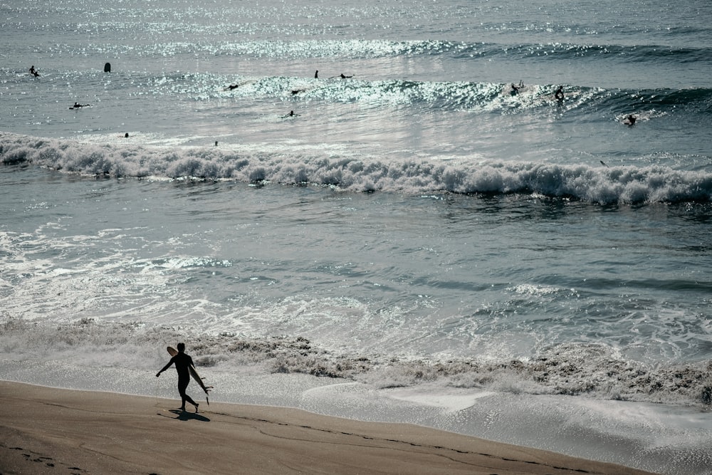 homem em shorts pretos andando na praia durante o dia