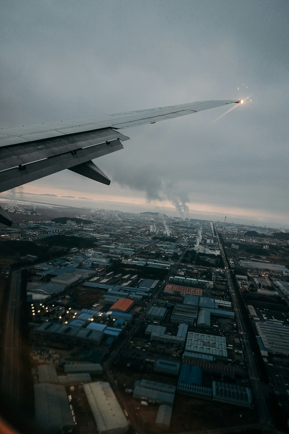 Ala bianca e grigia dell'aeroplano sopra la città durante il giorno