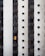 A tall, modern building facade with multiple vertical sections of dark windows is shown. A Spanish flag hangs prominently from one of the windows, adding a splash of color to the otherwise monochromatic scene.