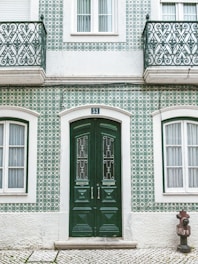 green wooden door on white concrete building