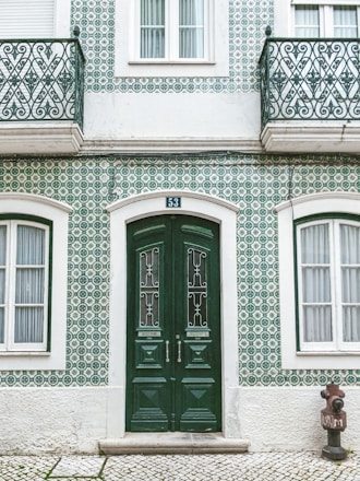 green wooden door on white concrete building