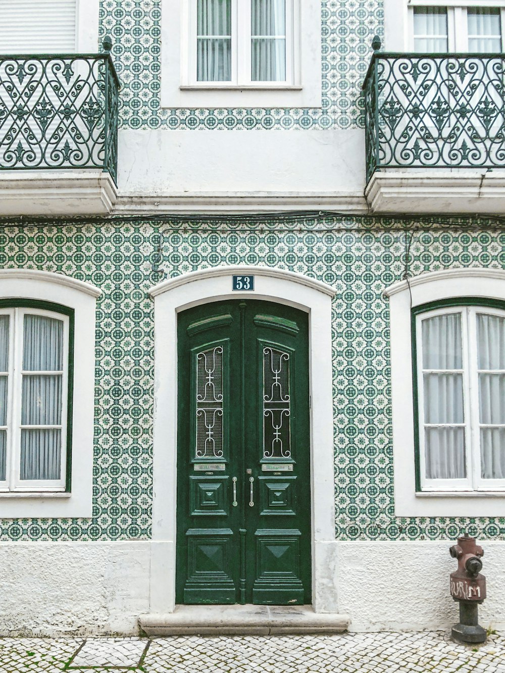 白いコンクリートの建物に緑の木のドア