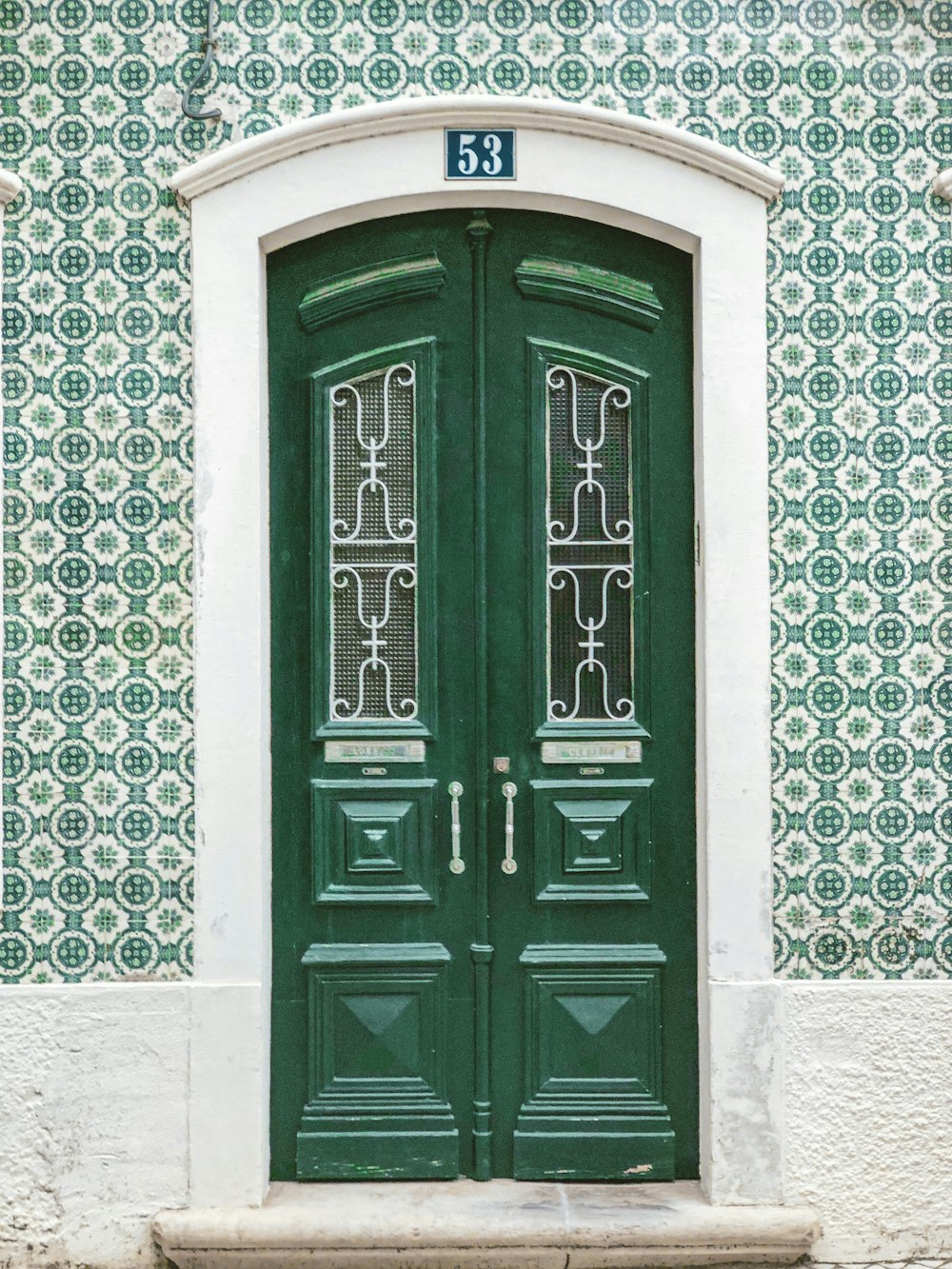 green wooden door on white concrete wall