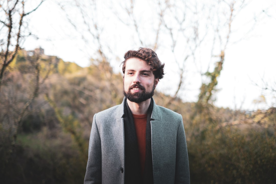 man in gray suit jacket standing near trees during daytime