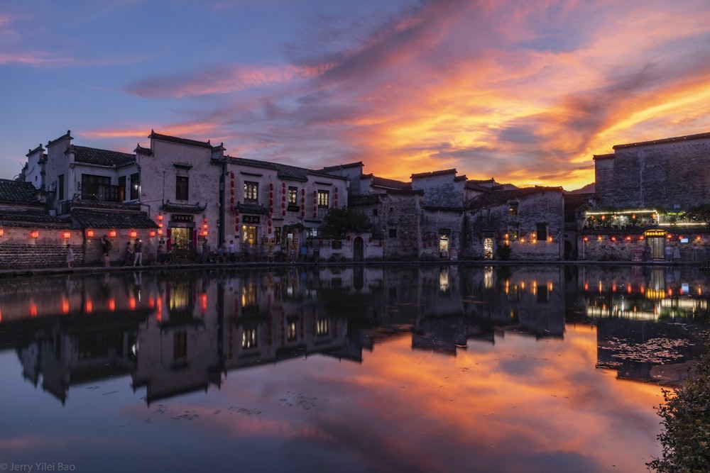 brown concrete building near body of water during sunset